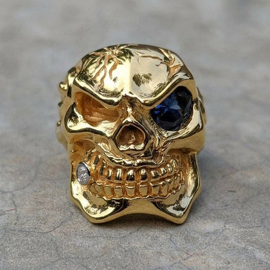Front view of handcrafted 925 sterling silver skull ring with 14K gold plating featuring blue gemstone eye and diamond accent