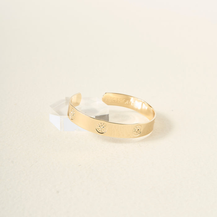The Darling Effect’s You Are Loving Cuff Bracelet, featuring embossed flower charms and the message "PIECES OF ME," is displayed on a clear acrylic stand against a cream background—a thoughtful gift for someone special.